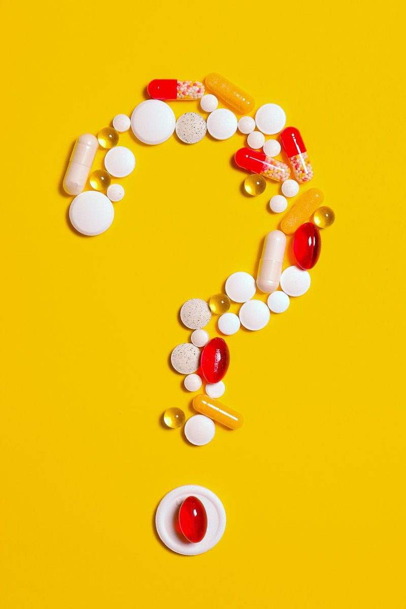 Assorted tablets and capsules arranged as a question mark on a bright yellow background